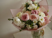 Bouquet of pink and white flowers in a clear vase on a light background